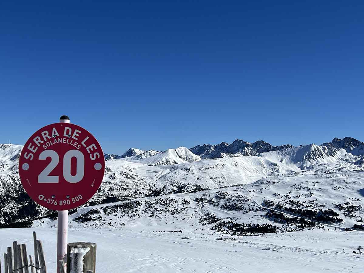 Piste sign in Andorra with snowy mountains beyond